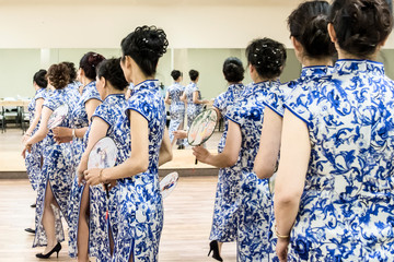 A group of women are practicing Cheongsam dress with blue flowers are practicing Chinese dancing	