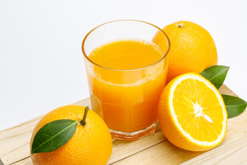 Glass of fresh orange juice with group of orange on a wooden box isolate on white background, Selective focus on glass.