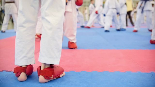 Karate training - group of karateka teenagers in red shoes and white kimono