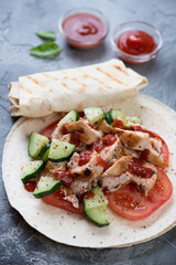 Shawarma with roasted chicken meat, fresh vegetables and tortilla bread. Studio shot, selective focus