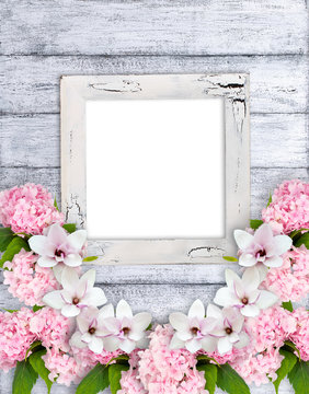 Magnolia flowers with hortensia and photo frame on background of shabby wooden planks in shabby chic style