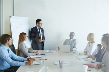 Group of white collar workers gathered together in modern board room while having training session