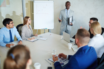 Obraz premium Group of young white collar workers analyzing financial report data while having work meeting in modern board room