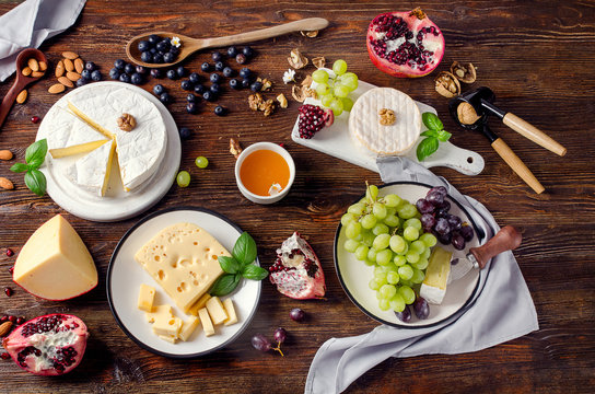 Cheese Brie with grapes and nuts on a dark wooden board