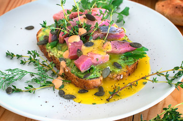 Sandwich with herring, avocado and egg yolk. Wooden background. Close-up. Top view