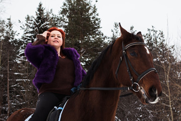 Fototapeta premium Woman with red hair and big horse outdoor in winter