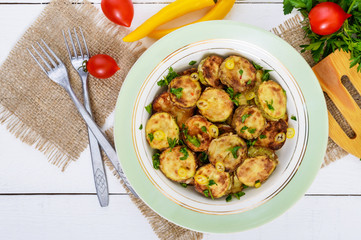 Fried slices of young zucchini with hot pepper, greens on a plate on a white wooden background. Top view. Vegetarian cuisine. Vegetable dish.