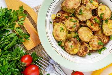 Fried slices of young zucchini with hot pepper, greens on a plate on a white wooden background. Top view. Close up. Vegetarian cuisine. Vegetable dish.