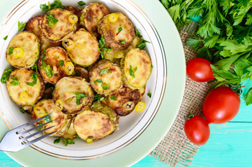 Fried slices of young zucchini with hot pepper, greens on a plate on a wooden background. Top view. Close up. Vegetarian cuisine. Vegetable dish.