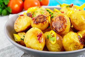 Baked potatoes with a golden crust with hot pepper, garlic, spices  and herbs in bowl.