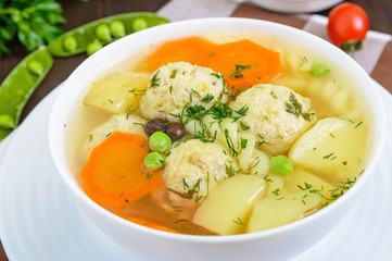 Light dietary soup with meat balls, vegetables, fusilli and boiled eggs on a dark wooden table. Useful lunch. Close up