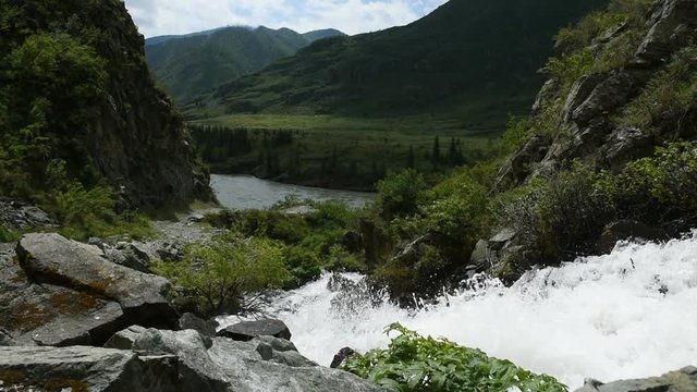 A mountain stream flows in the mountains into a deep valley.
