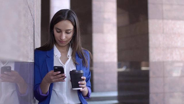 Business woman checks her phone standing in the city