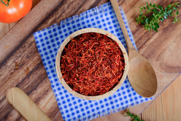 top view dried safflower in wooden bowl and on wooden cutting board