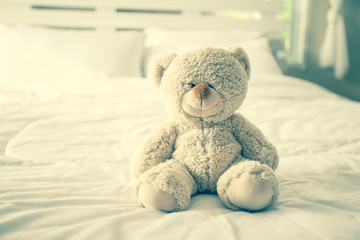 Teddy bear with depression sitting on the bed, vintage color tone.