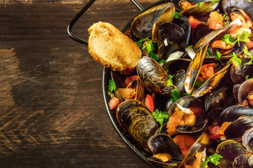 Skillet of marinara mussels on rustic background with copyspace