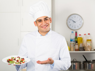 Male cook is demonstrating presentation of salad