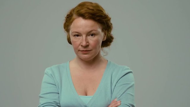 Mid aged actress showing different emotions and smiling. Red haired actress on the white background with thoughtful and laughing facial expression.