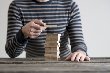 Man in stripped sweater placing wooden domino in a tower