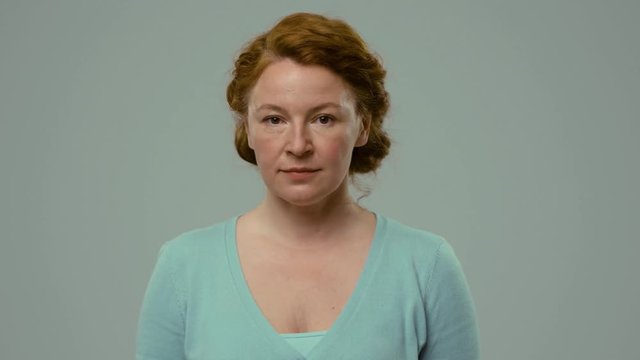 Actress of mid age showing emotions of anger and despite. Woman with foxy hair looking in camera with anger facial expression.