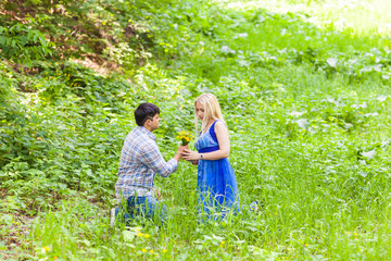 Fototapeta premium Young man giving a flower dandelion to girlfriend outdoors