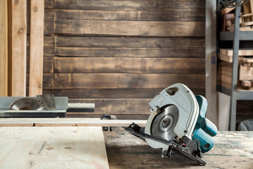 Circular saw lies on a wooden board in the workshop