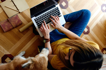 Young woman studying with her dog on the floor