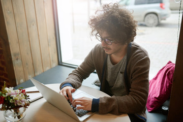 Young man working in cafe with laptop