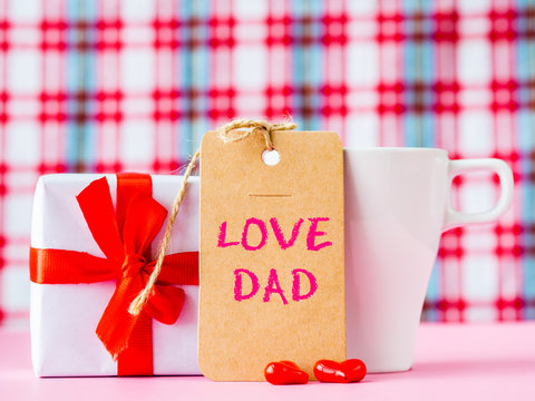 Father's day concept. I LOVE DAD message with coffee cup, two red heart and gift on pink background