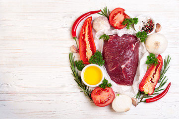 Raw meat with herbs, spices and seasoning on white wooden background, ingredients for cooking, top view. Beef meat, copy space