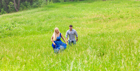 Naklejka na ściany i meble Happy couple running on a meadow in summer nature