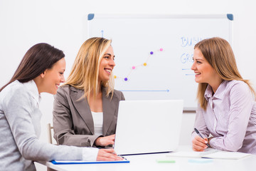 Three businesswomen are having meeting in their office. 