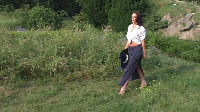 Woman walks on the grass in the park, she is happy and danced in the dance.
