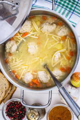 Meat broth with meatballs and spaghetti in a saucepan