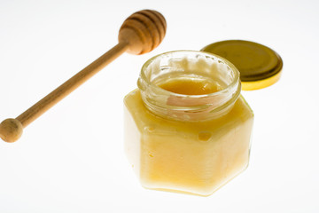 Spoon and honey in glass jar on white background