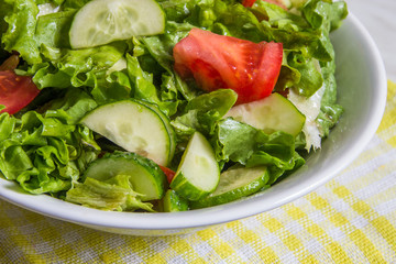 Fresh salad. Tomato, cucumber and greens in white bowl