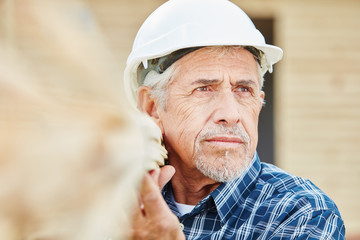 Senior Handwerker trägt Holz auf Baustelle