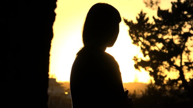 young woman's silhouette contemplating the sunset over the city