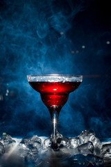 red cocktail with ice vapor, blue background