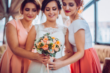 Happy bride and her charming bridesmaids in restaurant terace. Girls with flowers.