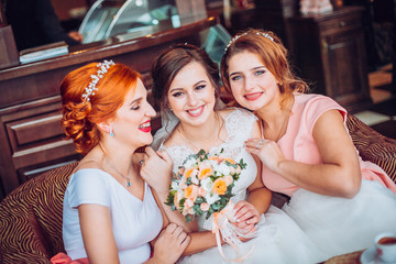 Happy bride and her charming bridesmaids in restaurant terace. Girls with flowers.