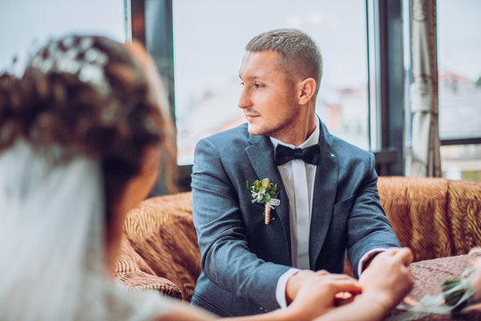 Cute married couple in cafe. Bride and groom in interior restaurant kiss each other.