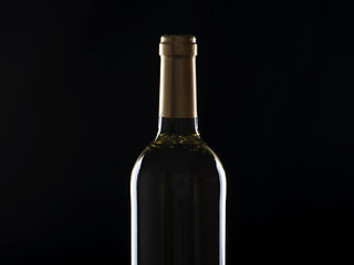 Bottle of white wine on wooden table. Backlighting. Horizontall studio shot.