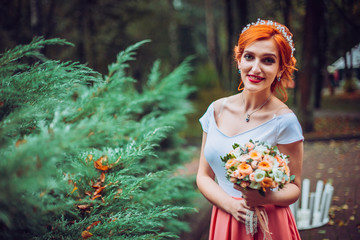Beautiful young bridesmaid posing on the park on the wedding day.