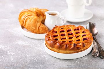 Breakfast - croissant, jam pie and coffee. Selective focus. Copy space.
