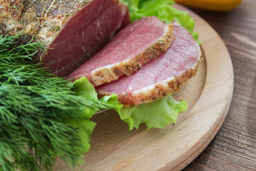 Slices of bacon, lettuce and fresh dill on a wooden plate. Selective focus.