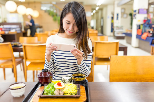 Woman taking photo on japanese cuisine in restaurant