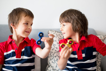 Little children, boy brothers, playing with colorful fidget spinner toys
