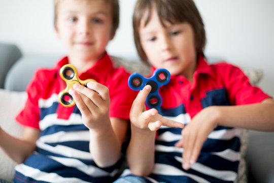 Little children, boy brothers, playing with colorful fidget spinner toys