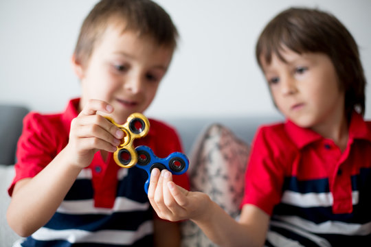 Little children, boy brothers, playing with colorful fidget spinner toys